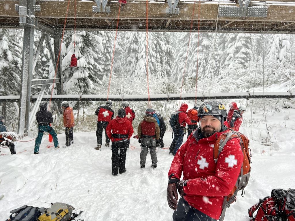 a picture of all members of the ski patrol standing in front of the patrol building