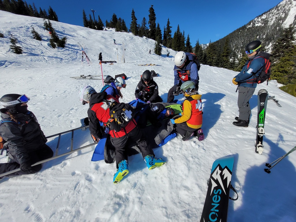 ski patrol candidates work together diligently to rescue a patient during a practice drill