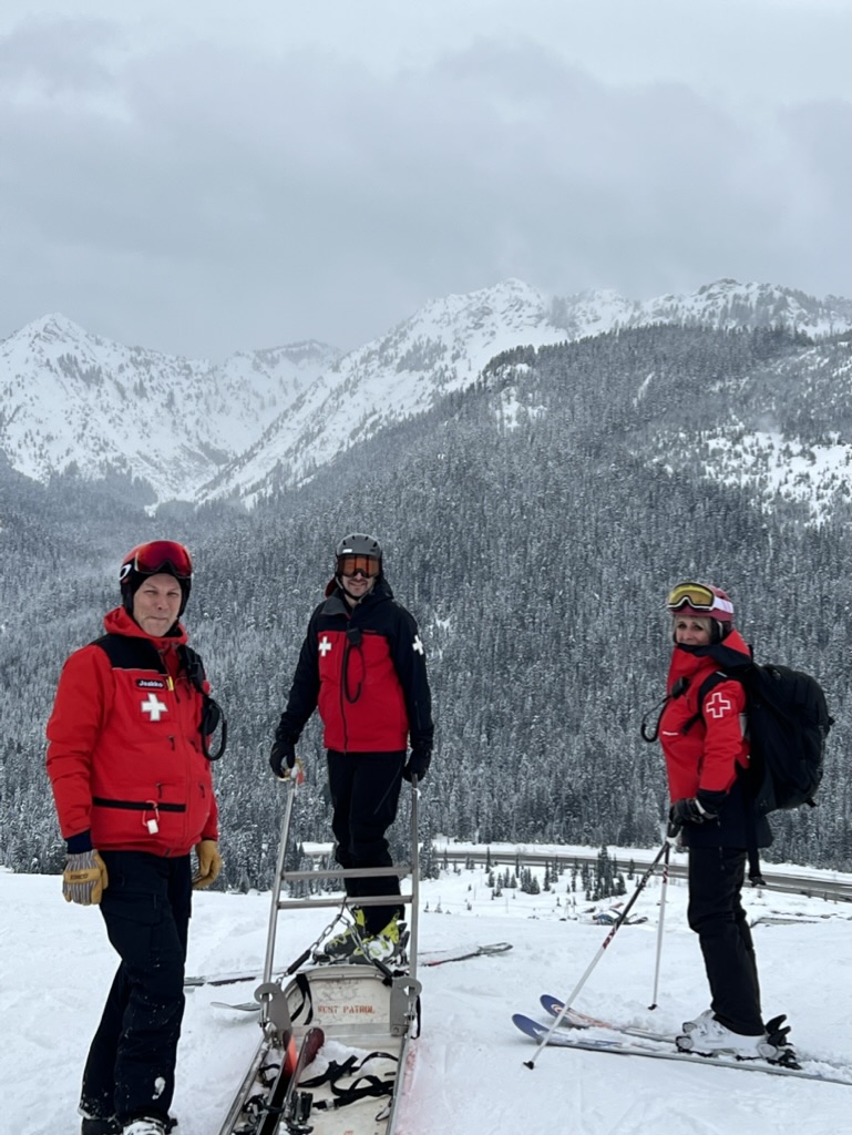 a picture of all members of the ski patrol standing in front of the patrol building